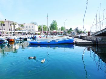 Boats moored at harbor against clear blue sky