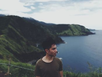 Young man standing by sea against sky