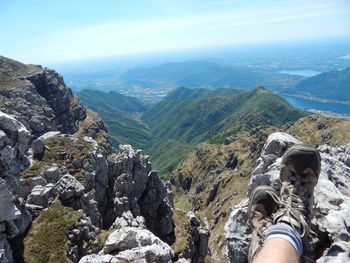 Low section of person on rock against sky