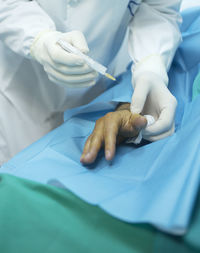 Midsection of doctor injecting patient in hospital