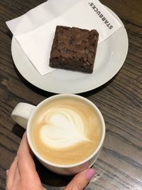 Cropped image of hand holding coffee cup on table