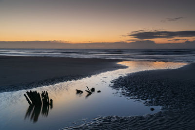 Scenic view of beach against sky during sunrise