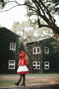 Full length of woman standing by house against building