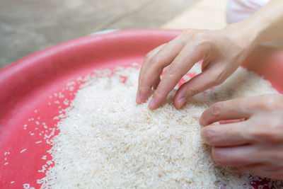 Woman hand holding rice in plastic tray. uncooked milled white rice. rice price in world market.