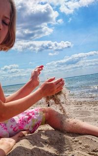 Midsection of woman on beach against sky