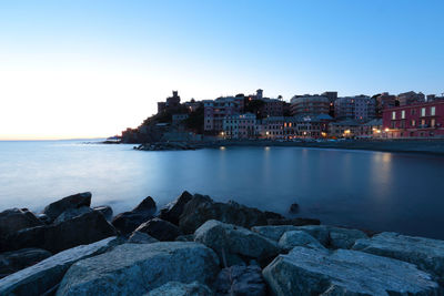 Scenic view of sea by buildings against clear sky