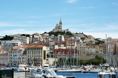 Boats moored at harbor against buildings in city