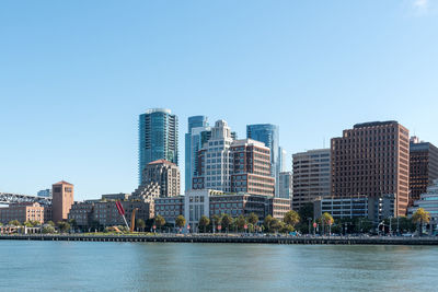 Sea by buildings against clear sky in city