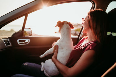 Woman with dog sitting in car