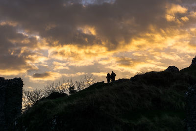 Low angle view of silhouette people standing on landscape against sky