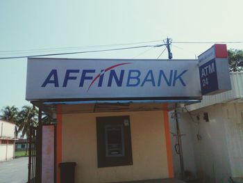 Low angle view of information sign on building against sky