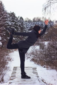Woman exercising on wooden structure during winter