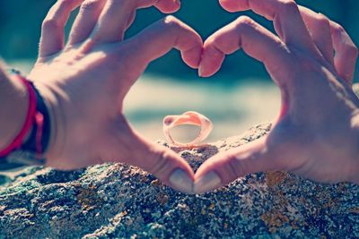 Close-up of hands holding heart shape against sea