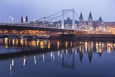 Illuminated bridge over river in city at night