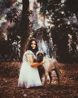 Portrait of young woman with dog in forest