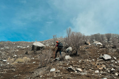 Man climbing on mountain against sky