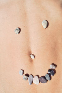 Midsection of woman with stones on stomach