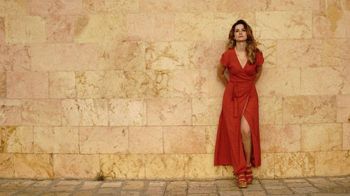 Portrait of woman standing against red wall