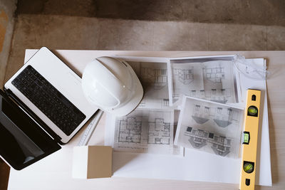 Blueprints, protective helmet, laptop,house model and tools on architect workspace.construction site