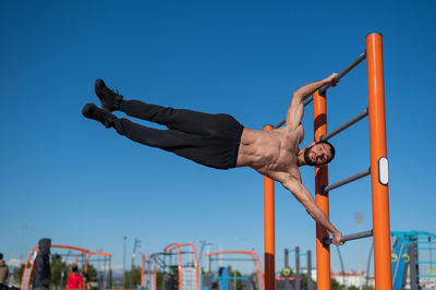 Shirtless man doing human flag outdoors. 