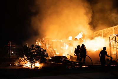 Silhouette people against illuminated fire at night