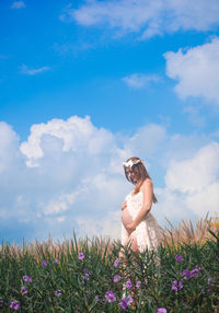 Pregnant woman standing on field against sky