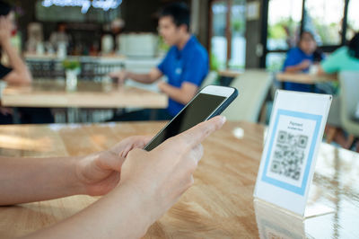 Cropped image of man using mobile phone on table