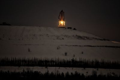 Built structure on snow covered land against sky at night