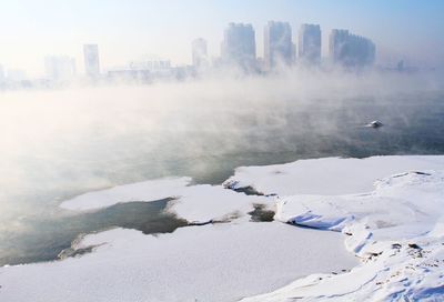 Aerial view of city by sea against sky during winter