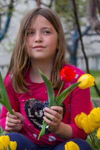 Portrait of woman holding girl sitting outdoors