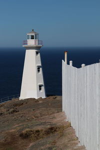 Lighthouse by sea against clear sky