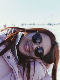Portrait of woman smiling while wearing sunglasses against sky