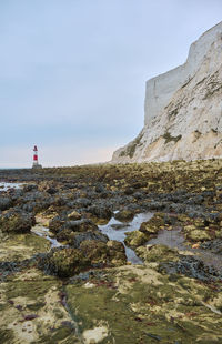 Lighthouse amidst buildings and sea against sky