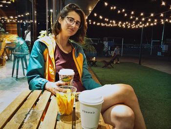 Portrait of young woman sitting at sidewalk cafe in city