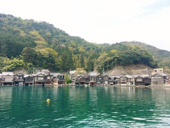 Houses by lake and buildings against sky