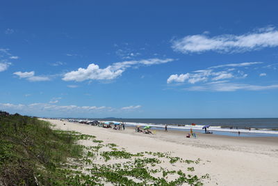 People at beach against blue sky