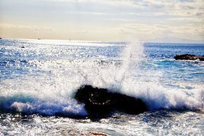 Waves splashing on sea against sky