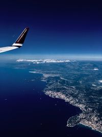 Airplane flying over sea against blue sky