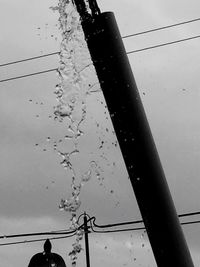 Low angle view of water drops on cable against sky