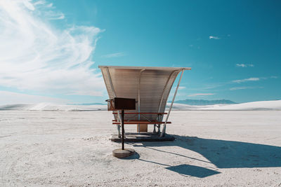 Chair on beach against sky on sunny day
