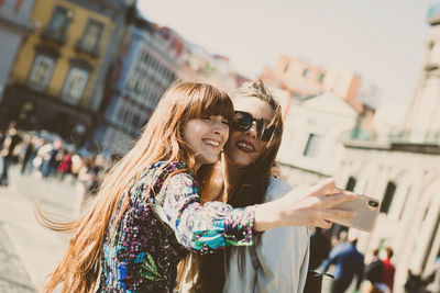 Portrait of happy friends standing against city in background