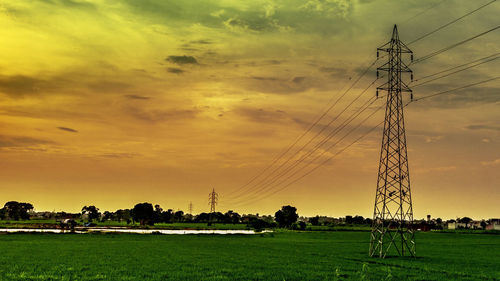 Electricity pylon on field against sky during sunset