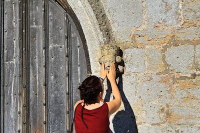 Rear view of women touching sculpture on wall