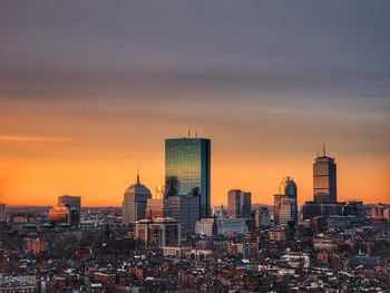 Modern buildings in city against sky during sunset