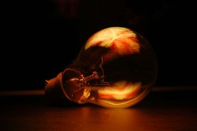 Close-up of illuminated ball on table against black background
