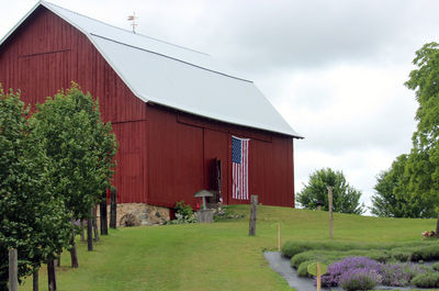 American flag on barn at field against sky