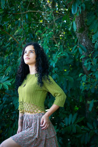 Portrait of beautiful young woman standing against tree