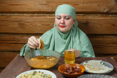 Portrait of young woman having food on table