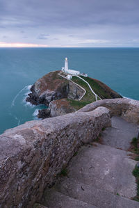 Lighthouse by sea against sky