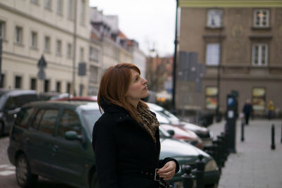 Woman standing by car on street in city